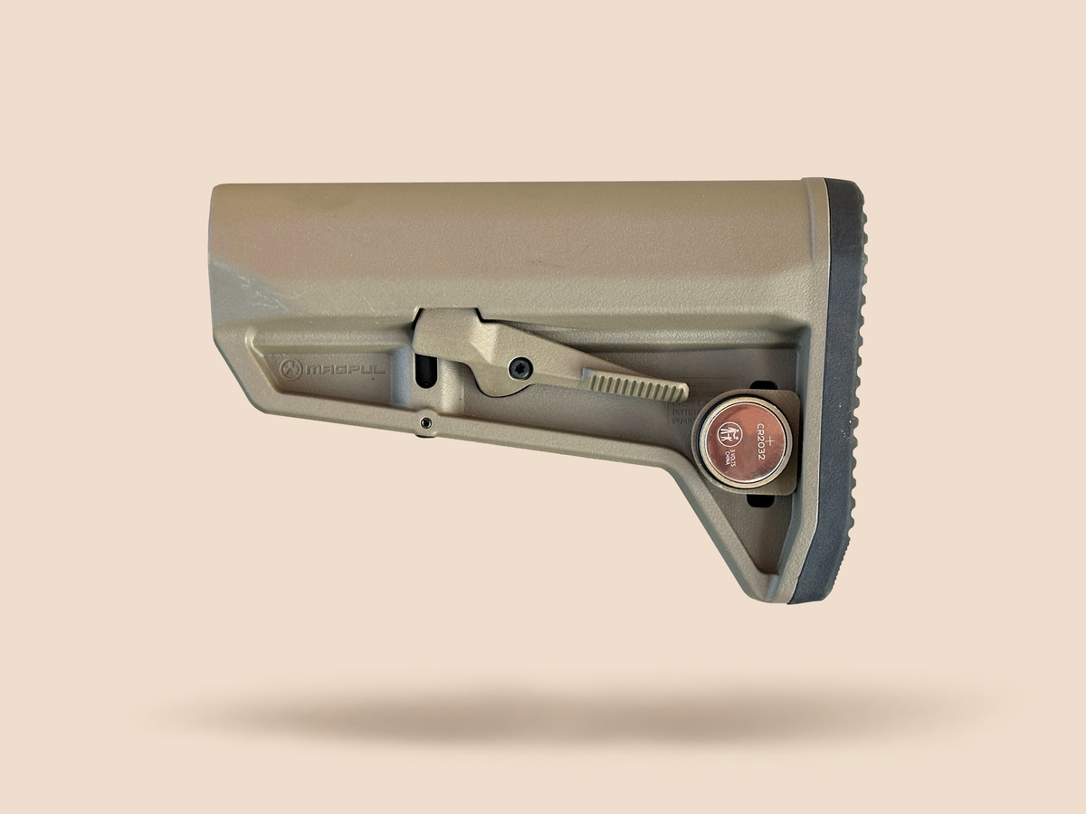 CHIP battery holder open on a tan rifle stock with a CR2032 battery seated inside
