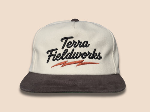 Lightning Bolt Snapback Hat in cream/black with black puff embroidered Terra Fieldworks script and orange lightning bolt